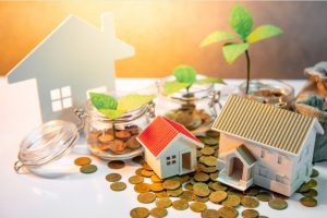 Imagen de una casa junto a monedas, representando inversión inmobiliaria en Galicia con Housefulness.